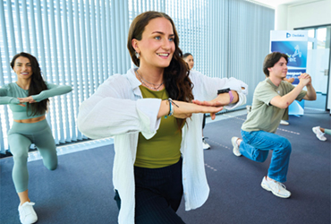 Menschen bewegen: Interview mit Stefanie Heinen, Dedalus HealthCare. Dienstagmittag, 12:30 Uhr. In Raum C2.2 des Bonner Headquarters treffen sich fünf Mitarbeiterinnen und Mitarbeiter, einige im Sportoutfit, andere in normaler Kleidung. 30 weitere haben sich aus dem Homeoffice online dazugeschaltet. Die „Bewegte Pause“ steht an, ein Angebot des Betrieblichen Gesundheitsmanagements, um den Mitarbeiterinnen und Mitarbeitern mit Dehnen, Stretchen, Mobilisations- und leichten Kraftübungen eine halbstündige Auszeit von der Arbeit zu ermöglichen.