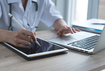 Médico trabajando con ordenador y tablet